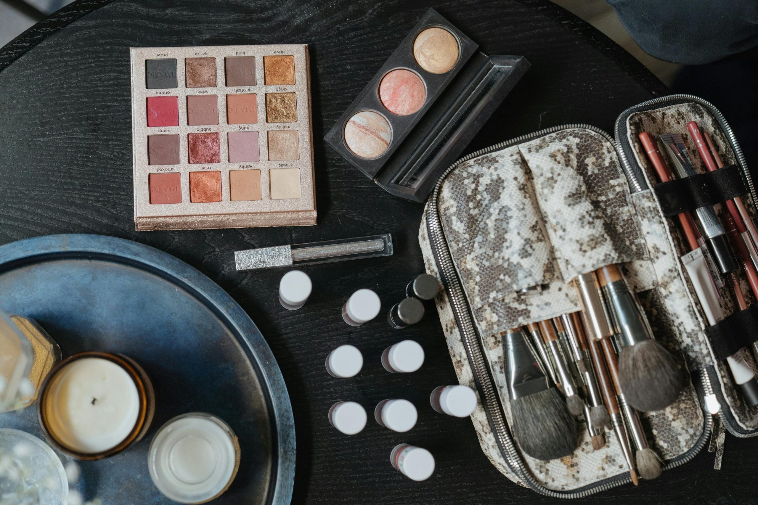 A makeup artist's kit displaying palettes, brushes, adhesive gels, and gems