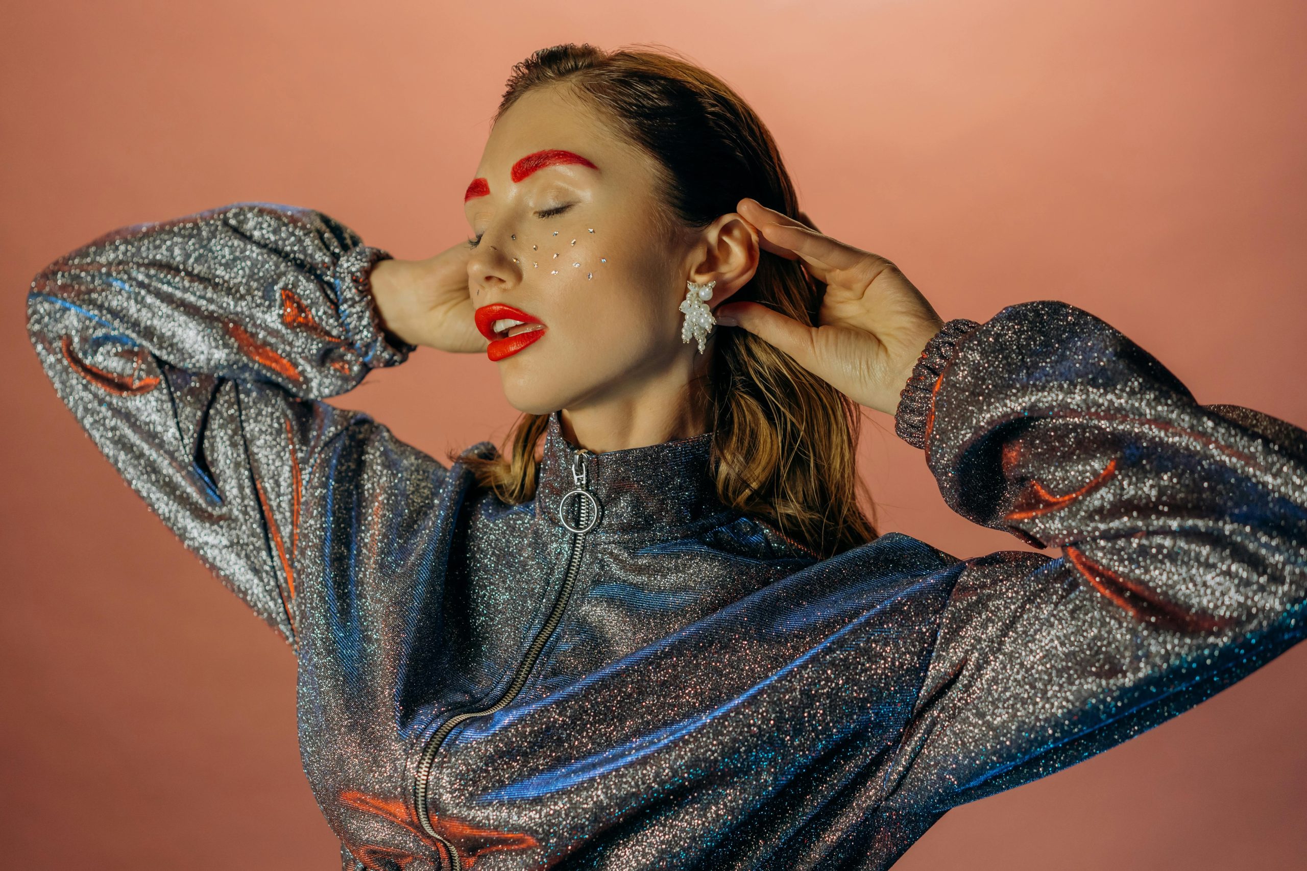A model wearing metallic blue and silver eye makeup with glowing accents