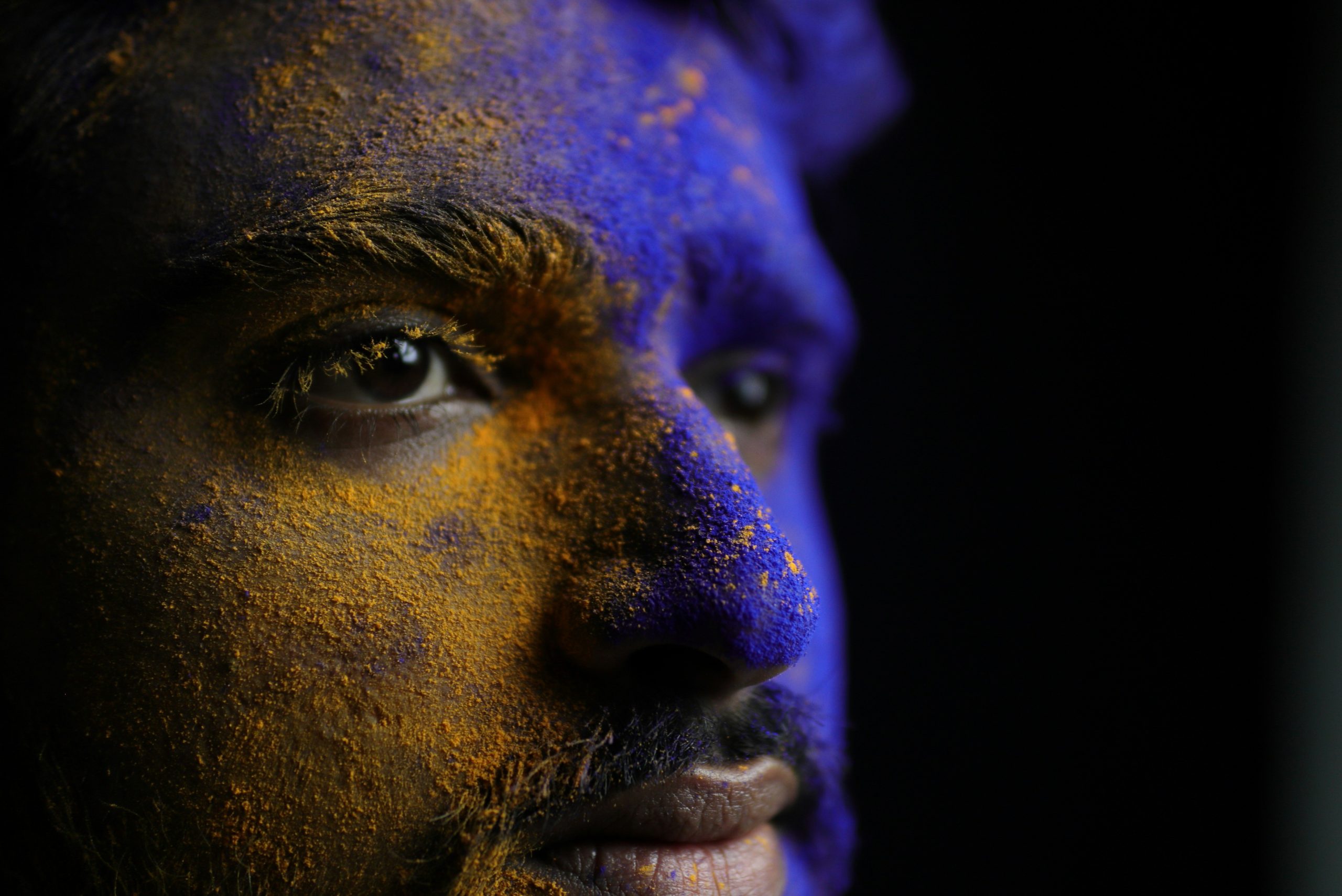 A close-up of smudged blue-and-purple fantasy makeup on a performer's face