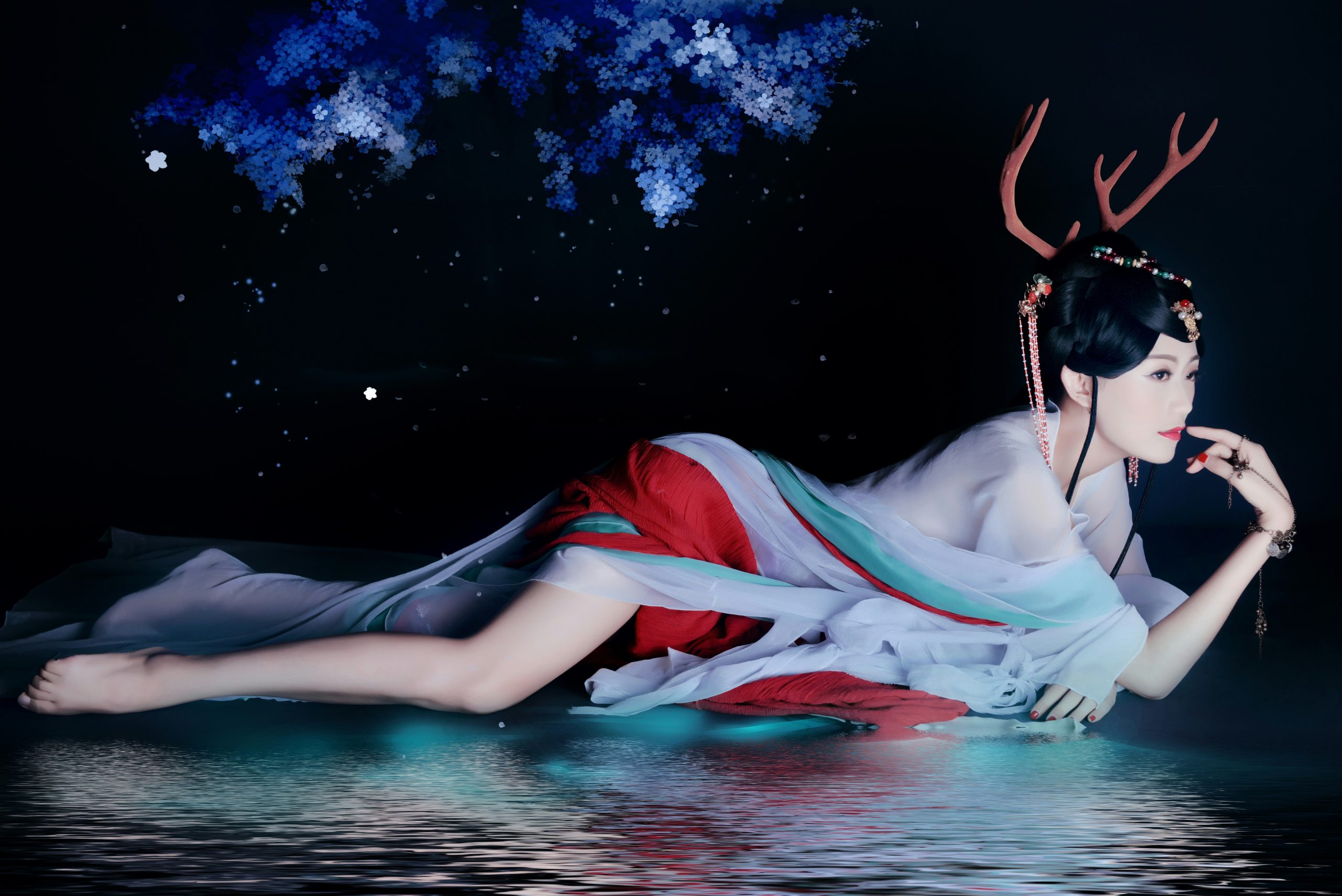 A woman dressed as a mystical mermaid with glittery makeup and scales painted on her arm.