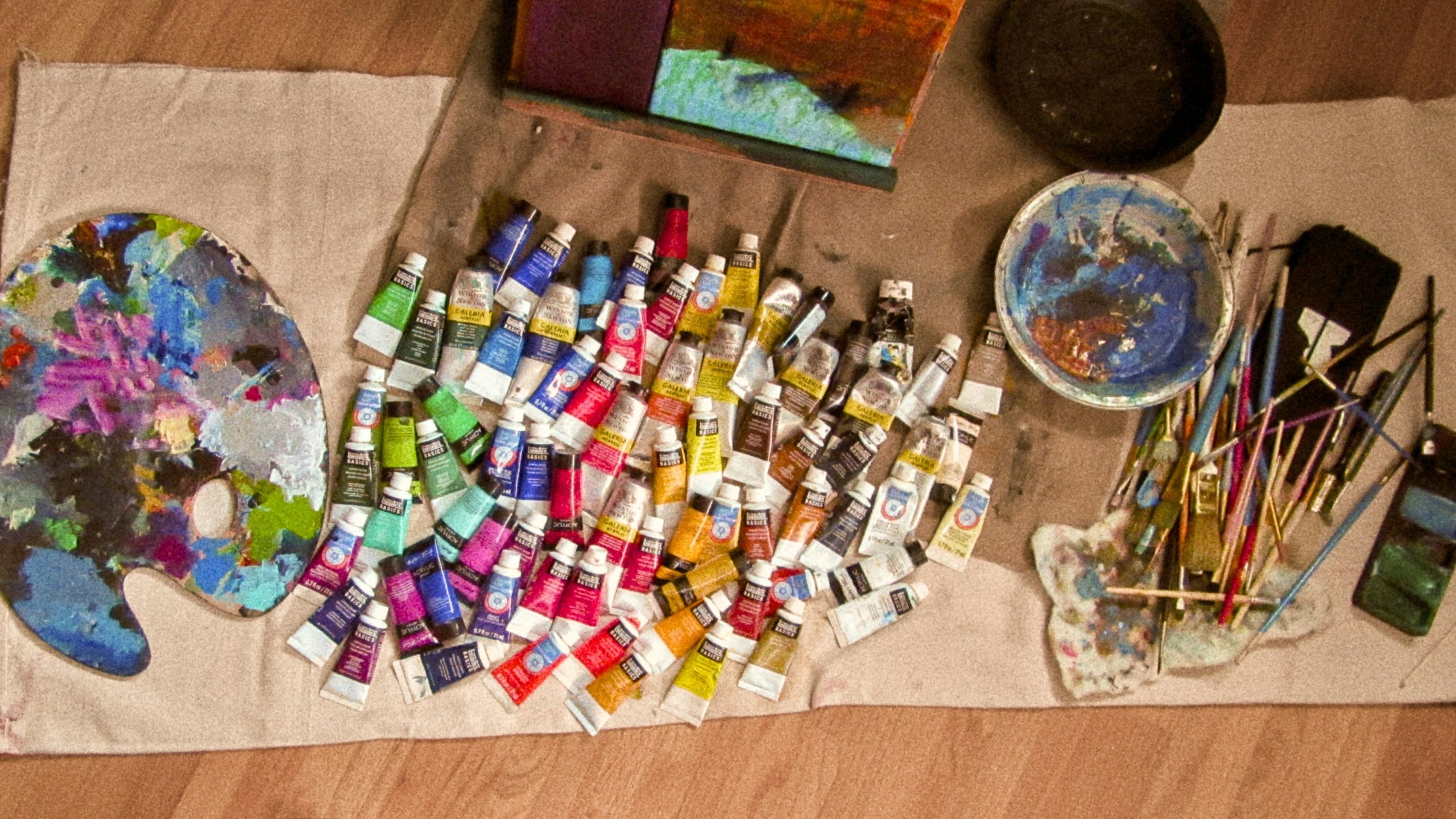 An array of colorful eyeshadows laid out next to brushes.