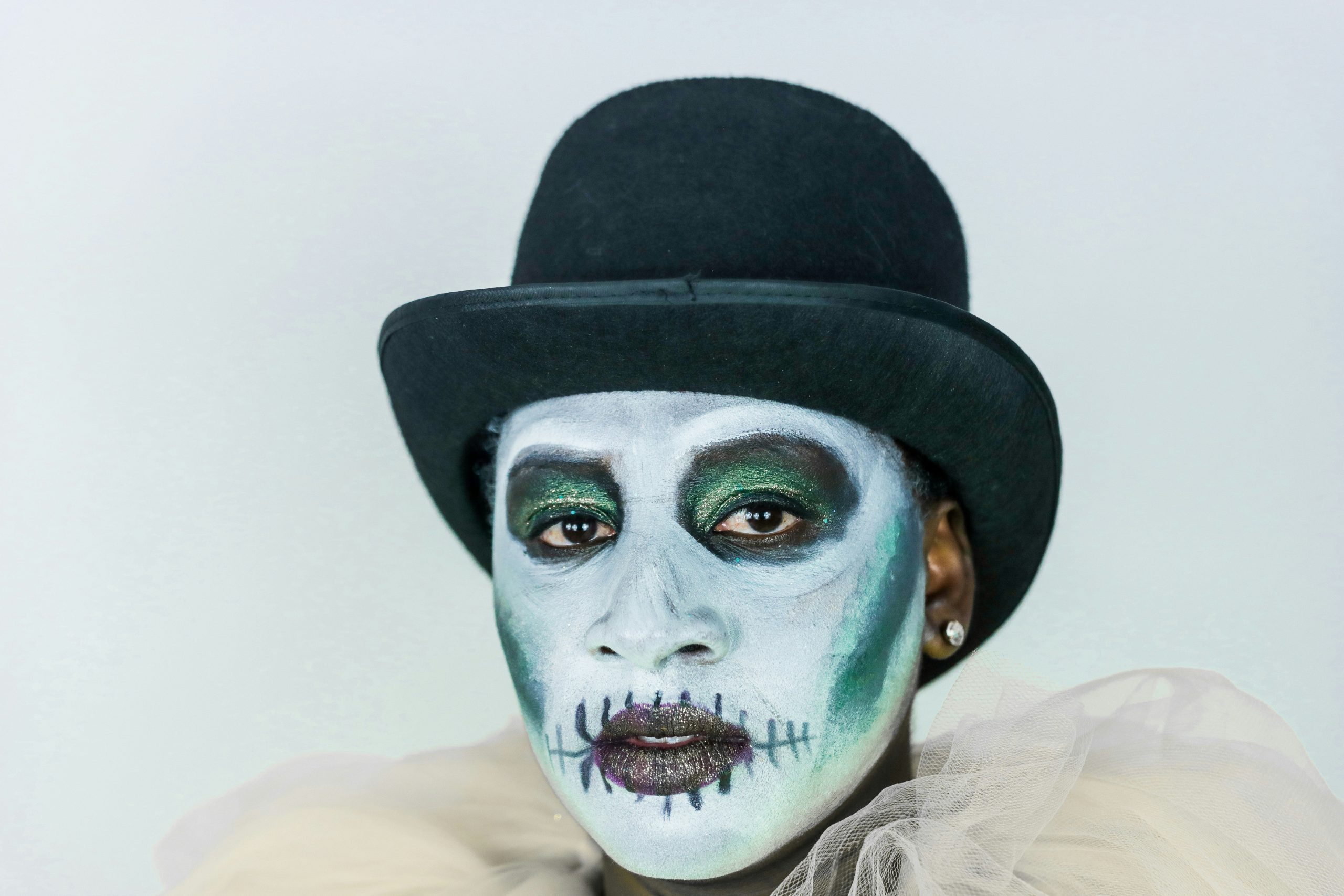 A frustrated person holding makeup brushes near smeared skeleton face paint