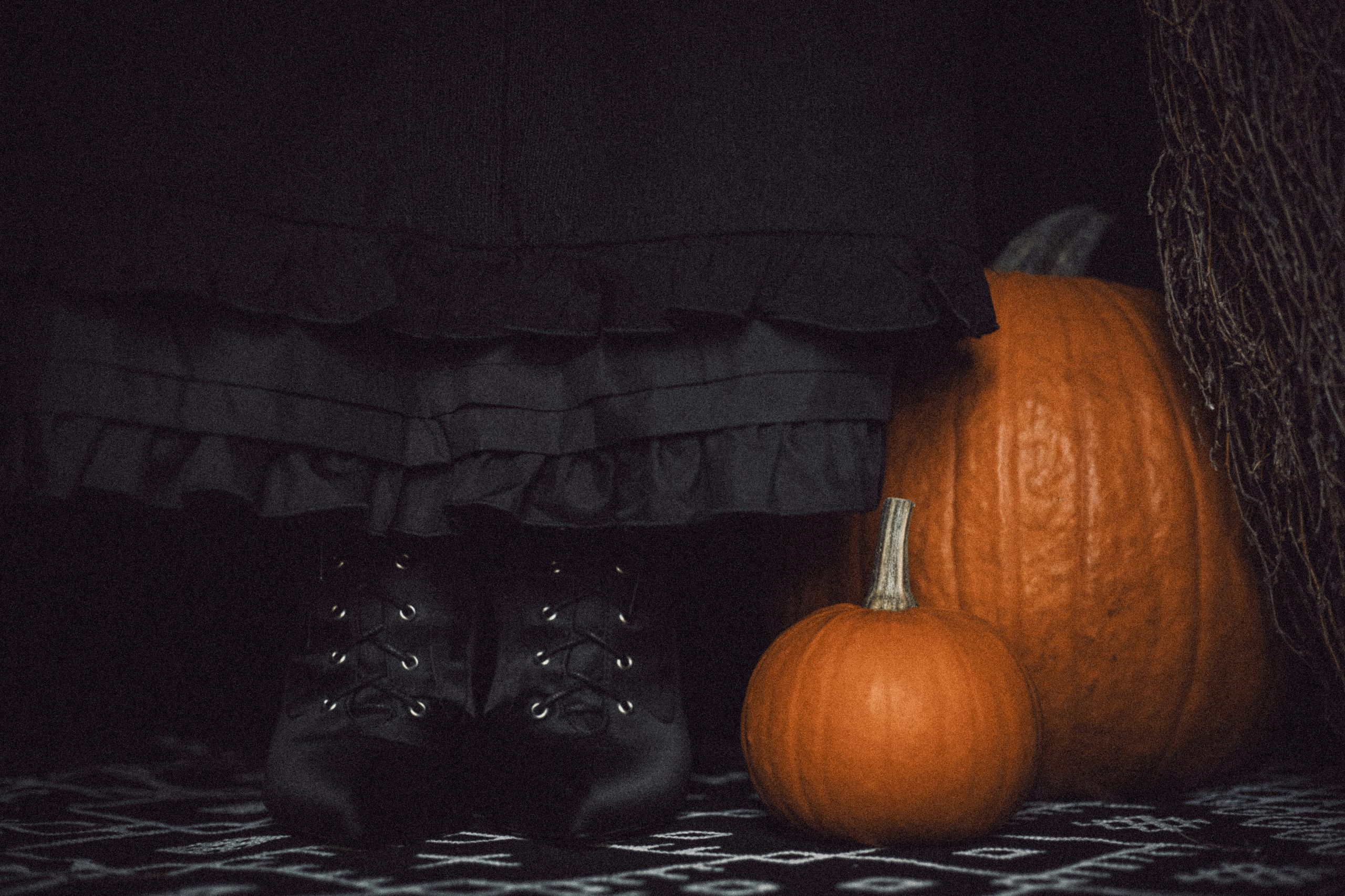 A person in black boots next to pumpkins
