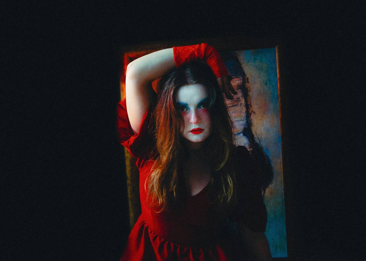 A close-up of vibrant Halloween stage makeup featuring bold reds, blacks, and metallic accents.